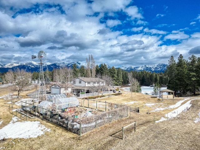view of yard with fence, a greenhouse, a vegetable garden, a mountain view, and an outbuilding