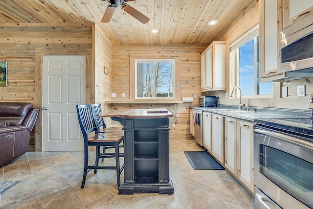 kitchen featuring wooden walls, appliances with stainless steel finishes, and wood ceiling