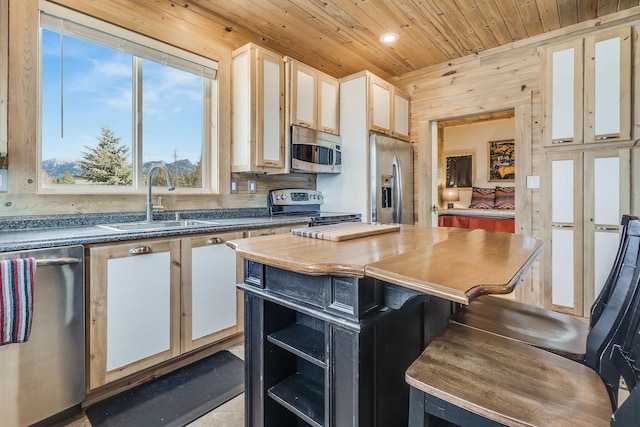 kitchen with a sink, wood walls, stainless steel appliances, recessed lighting, and wooden ceiling