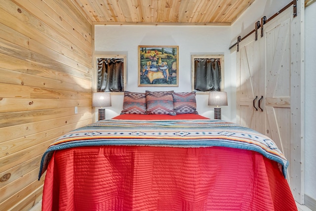 bedroom with wooden walls, wood ceiling, and a barn door