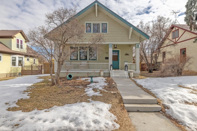 bungalow-style home with covered porch and fence