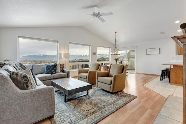 living area featuring lofted ceiling, light wood-style flooring, ceiling fan with notable chandelier, a mountain view, and recessed lighting