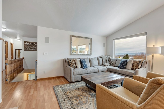 living area featuring light wood finished floors, baseboards, visible vents, and vaulted ceiling