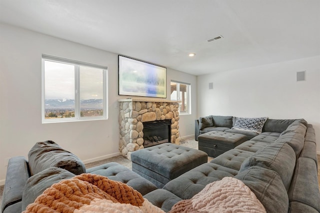 living room featuring baseboards, a fireplace, visible vents, and light colored carpet