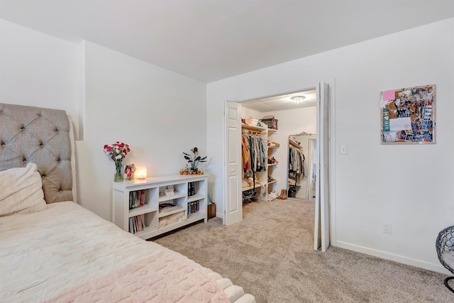 bedroom featuring a closet, a spacious closet, baseboards, and carpet flooring