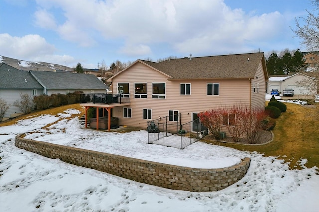 snow covered property featuring a wooden deck and a hot tub