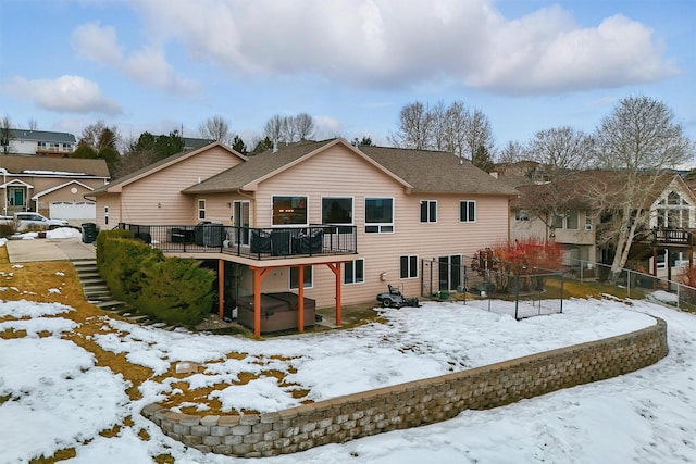 snow covered property with a hot tub, fence, and a wooden deck