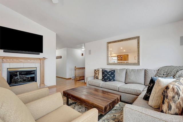 living room with visible vents, baseboards, wood finished floors, and a tile fireplace