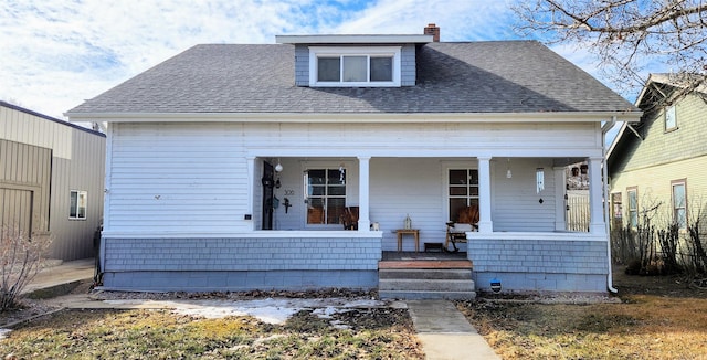 bungalow-style house with covered porch, a chimney, and roof with shingles