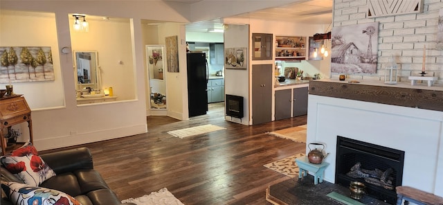 living area featuring a fireplace, dark wood finished floors, and baseboards