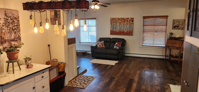 sitting room featuring dark wood-style floors, baseboard heating, and a ceiling fan