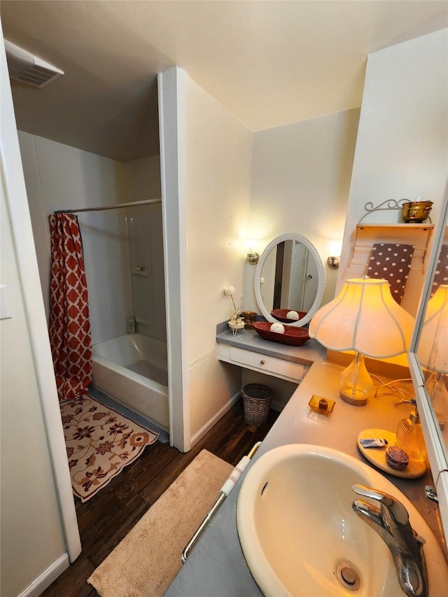 full bathroom with visible vents, shower / tub combo, a sink, wood finished floors, and baseboards