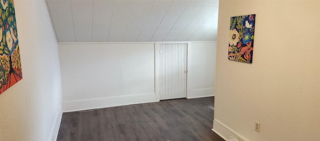 interior space with dark wood-type flooring, a textured wall, and baseboards