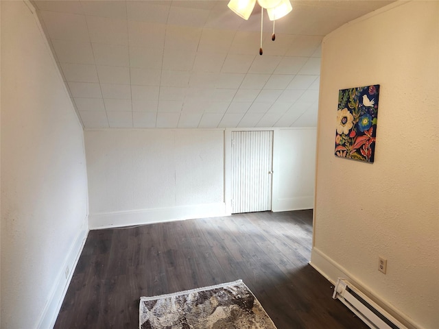 additional living space with a textured wall, baseboard heating, dark wood finished floors, and baseboards