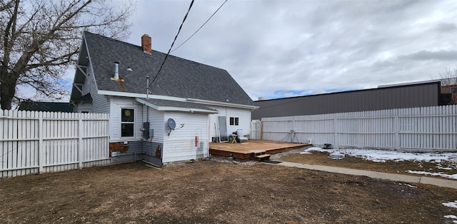 rear view of property featuring a fenced backyard, a chimney, roof with shingles, and a wooden deck