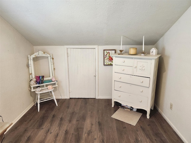 bedroom featuring a textured ceiling, baseboards, and wood finished floors