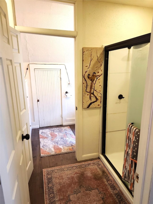 interior space with a textured wall, baseboards, and wood finished floors