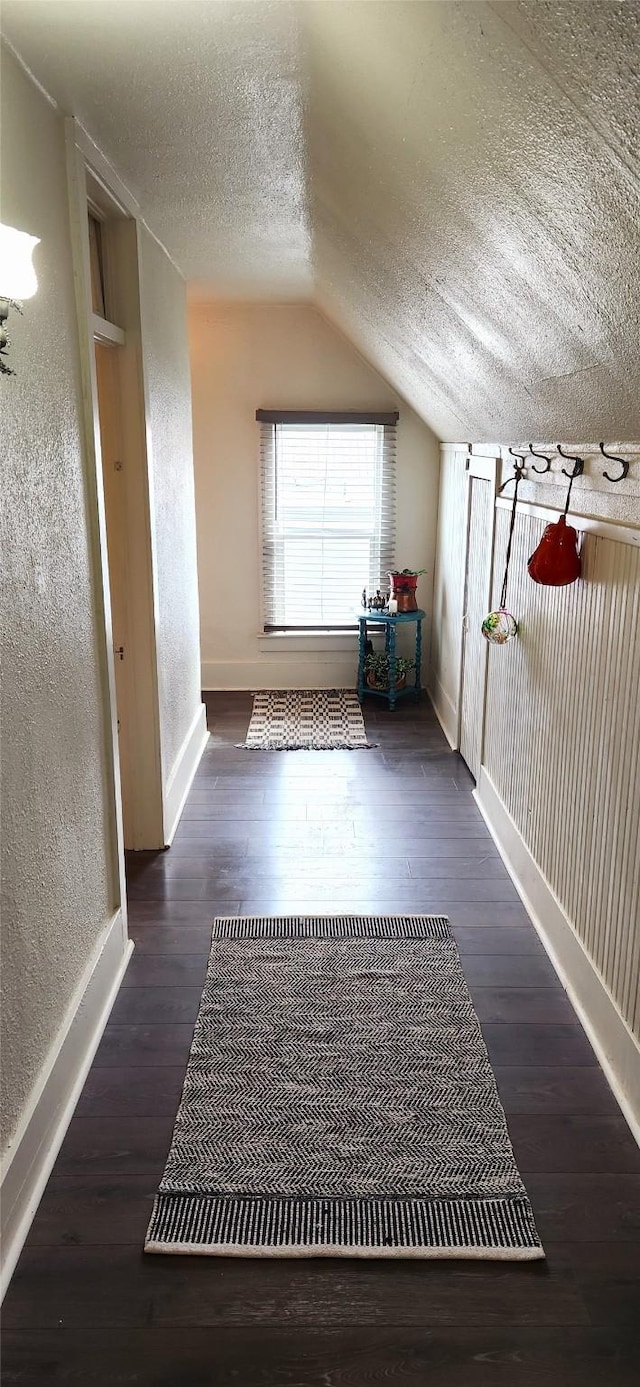 bonus room with a textured ceiling, a textured wall, and wood finished floors