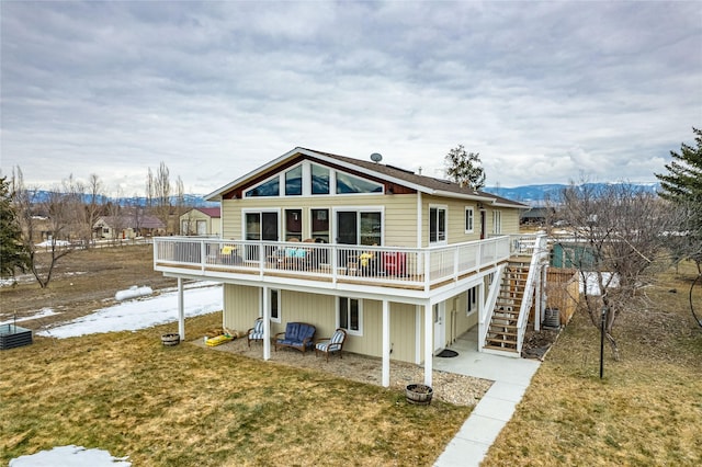 rear view of house with a deck with mountain view, stairway, a lawn, and central air condition unit