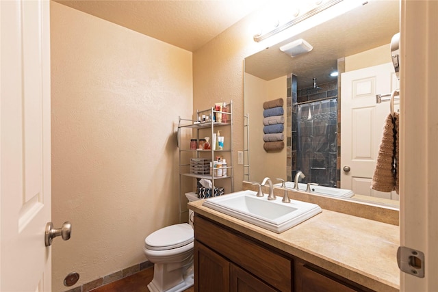 full bath featuring a textured wall, a tile shower, vanity, and toilet