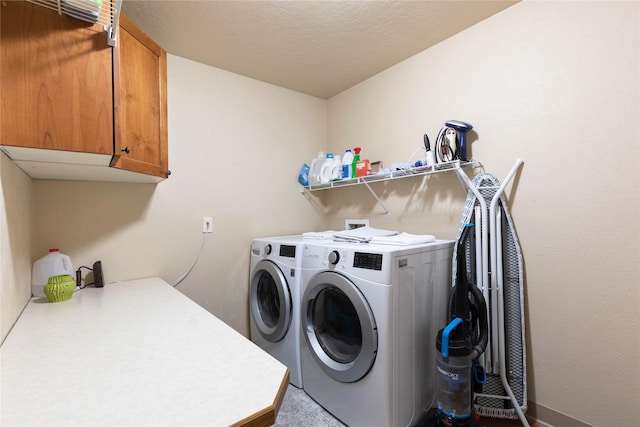 clothes washing area with a textured ceiling, separate washer and dryer, and cabinet space