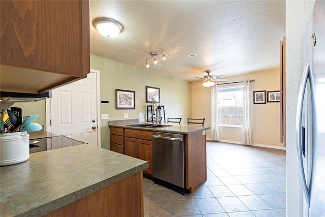 kitchen with ceiling fan, appliances with stainless steel finishes, a peninsula, a textured ceiling, and a sink