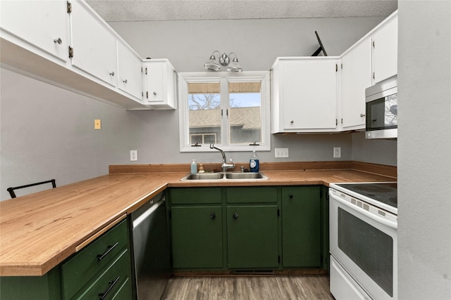 kitchen with appliances with stainless steel finishes, a sink, white cabinetry, and light wood-style floors