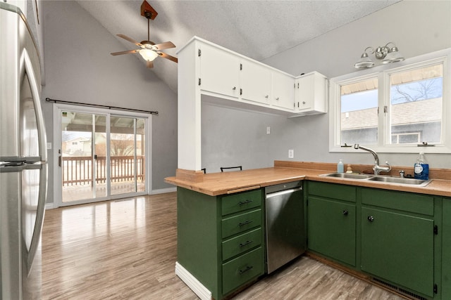 kitchen with stainless steel appliances, light countertops, light wood-style flooring, white cabinetry, and a sink