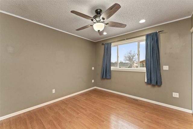 spare room featuring baseboards, wood finished floors, and crown molding