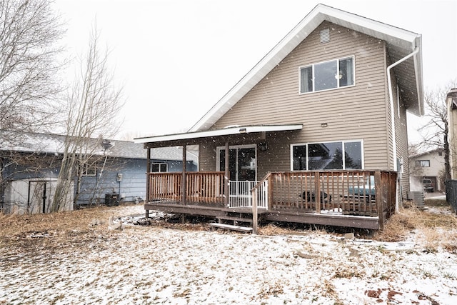 snow covered rear of property with cooling unit and a wooden deck