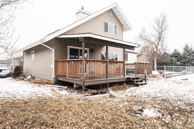 snow covered property with fence and a wooden deck