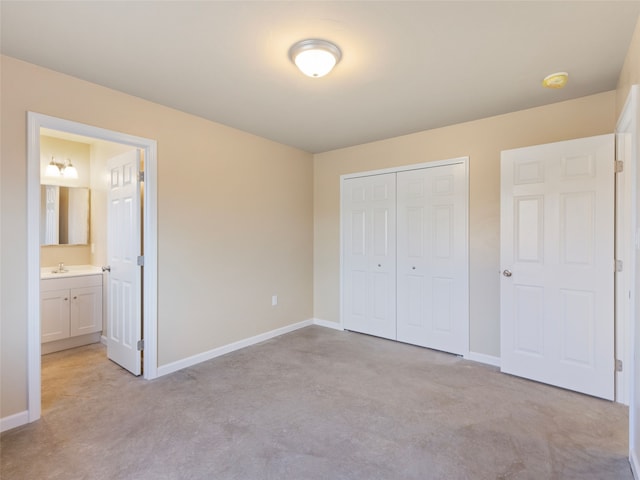 unfurnished bedroom with concrete floors, a closet, a sink, and baseboards