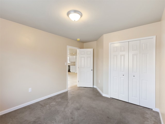 unfurnished bedroom featuring baseboards, concrete flooring, and a closet