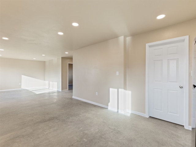 empty room with finished concrete flooring, baseboards, and recessed lighting