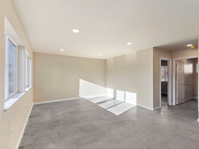 empty room featuring recessed lighting, a healthy amount of sunlight, finished concrete flooring, and baseboards