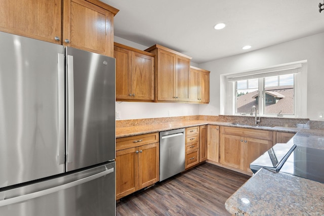 kitchen with recessed lighting, dark wood-style flooring, a sink, appliances with stainless steel finishes, and light stone countertops