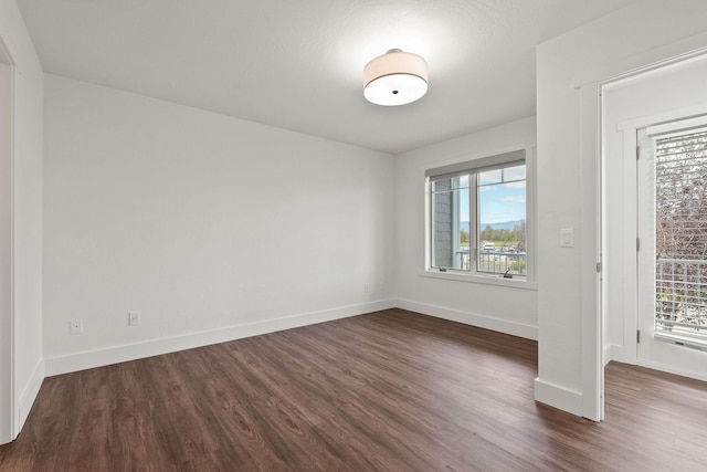 unfurnished room featuring dark wood-style floors, plenty of natural light, and baseboards