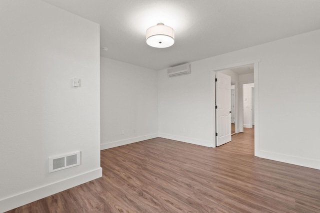 empty room with baseboards, visible vents, wood finished floors, and a wall mounted AC