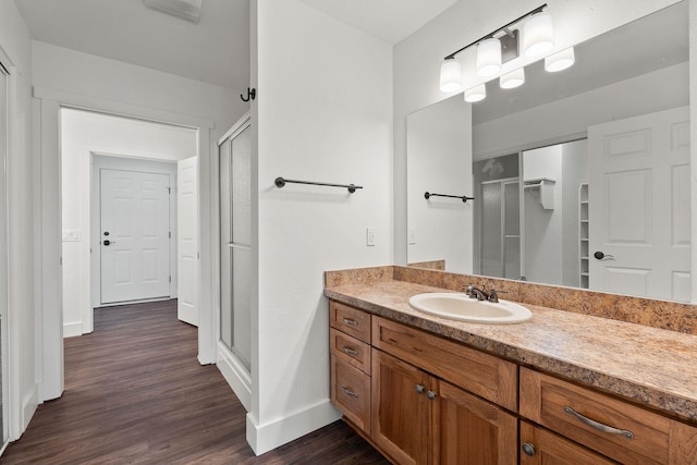 full bathroom featuring a stall shower, wood finished floors, vanity, and baseboards