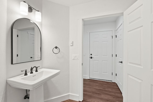 bathroom with a sink, a textured wall, wood finished floors, and baseboards