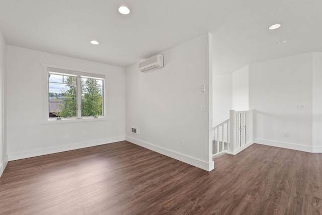 empty room with visible vents, baseboards, dark wood-type flooring, an AC wall unit, and recessed lighting