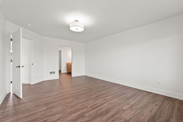 spare room with dark wood-style floors, baseboards, and visible vents