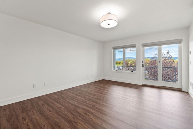 unfurnished room with dark wood-style floors and baseboards