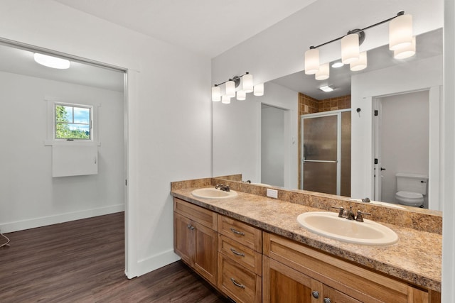 full bath featuring a stall shower, wood finished floors, a sink, and double vanity