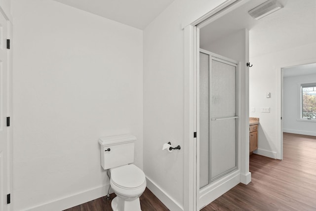 bathroom featuring a shower stall, baseboards, wood finished floors, and vanity