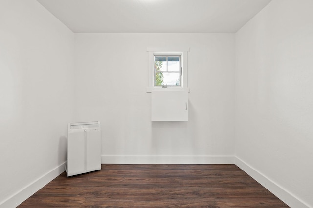 empty room with baseboards and dark wood-type flooring