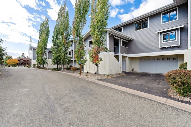 view of front of property featuring an attached garage, a residential view, and aphalt driveway