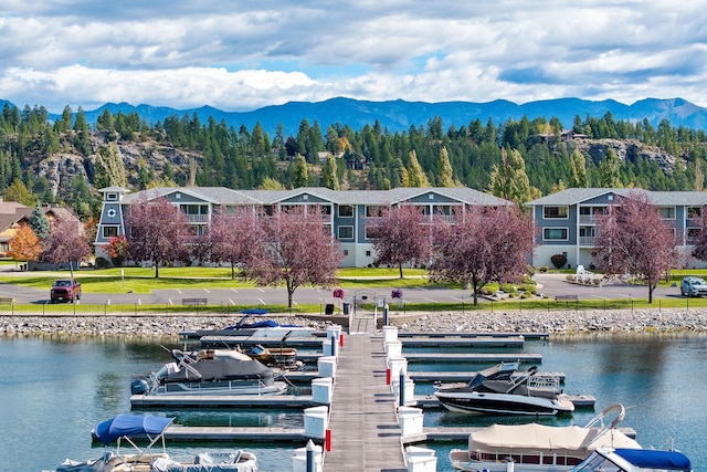 view of dock featuring a lawn and a water and mountain view