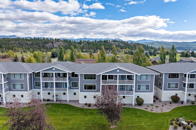 rear view of property featuring a yard, a residential view, and a mountain view