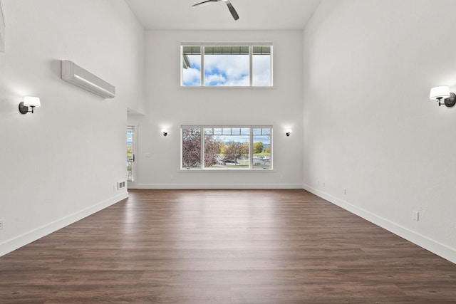 unfurnished living room with dark wood-style floors, a high ceiling, baseboards, and a ceiling fan